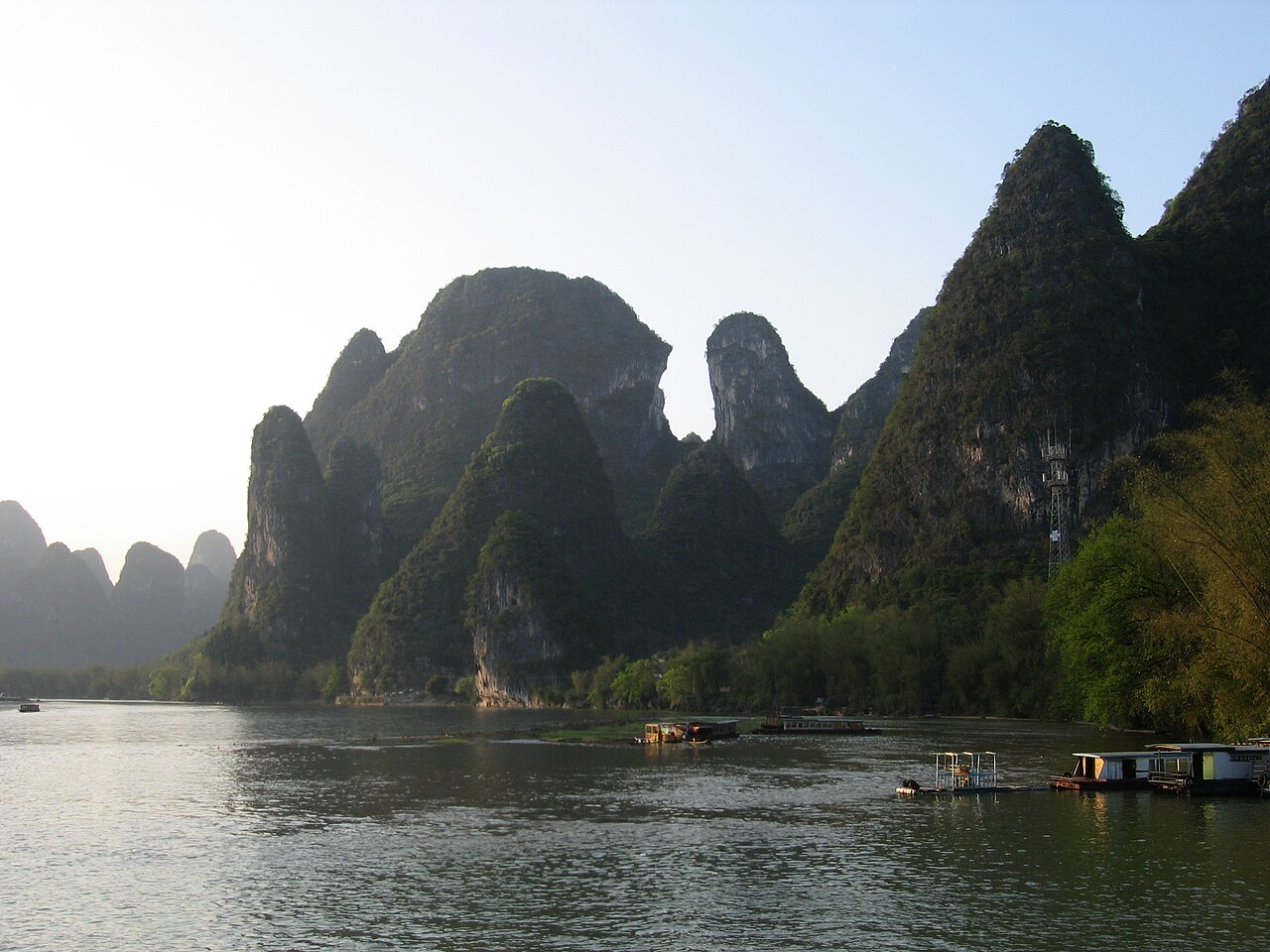 Boats on the Li River at Xingping in the Guilin region, surrounded by limestone peaks in warm evening light.
